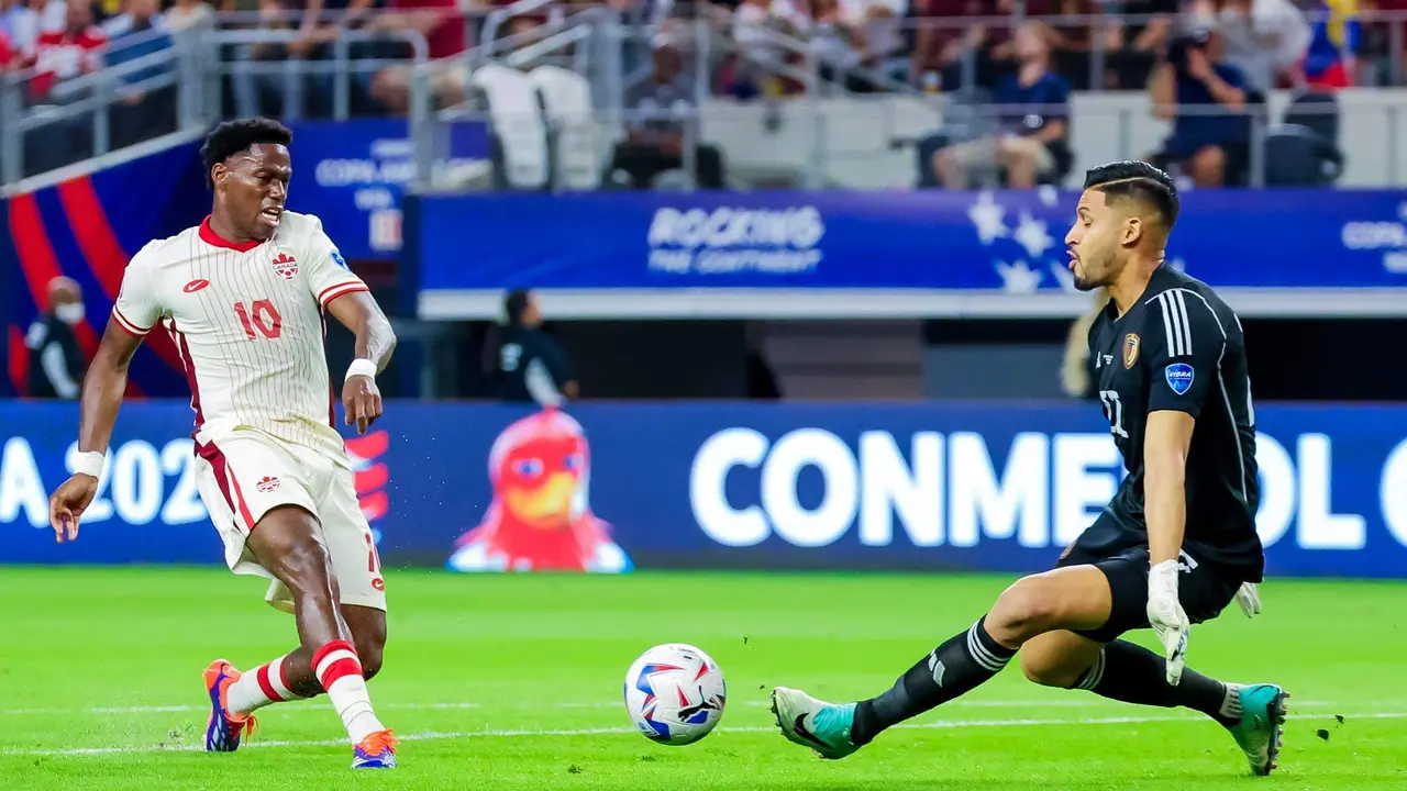 El guardameta de Venezuela, Rafael Romo (d), fue registrado este viernes, 5 de julio, al intentar bloquearle un bal&oacute;n disparado por el delantero canadiense Jonathan David (i), durante el segundo partido de los cuartos de final de la Copa Am&eacute;rica 2024, en el estadio AT&T de Arlington (Texas, EE.UU.). EFE/Kevin Jairaj